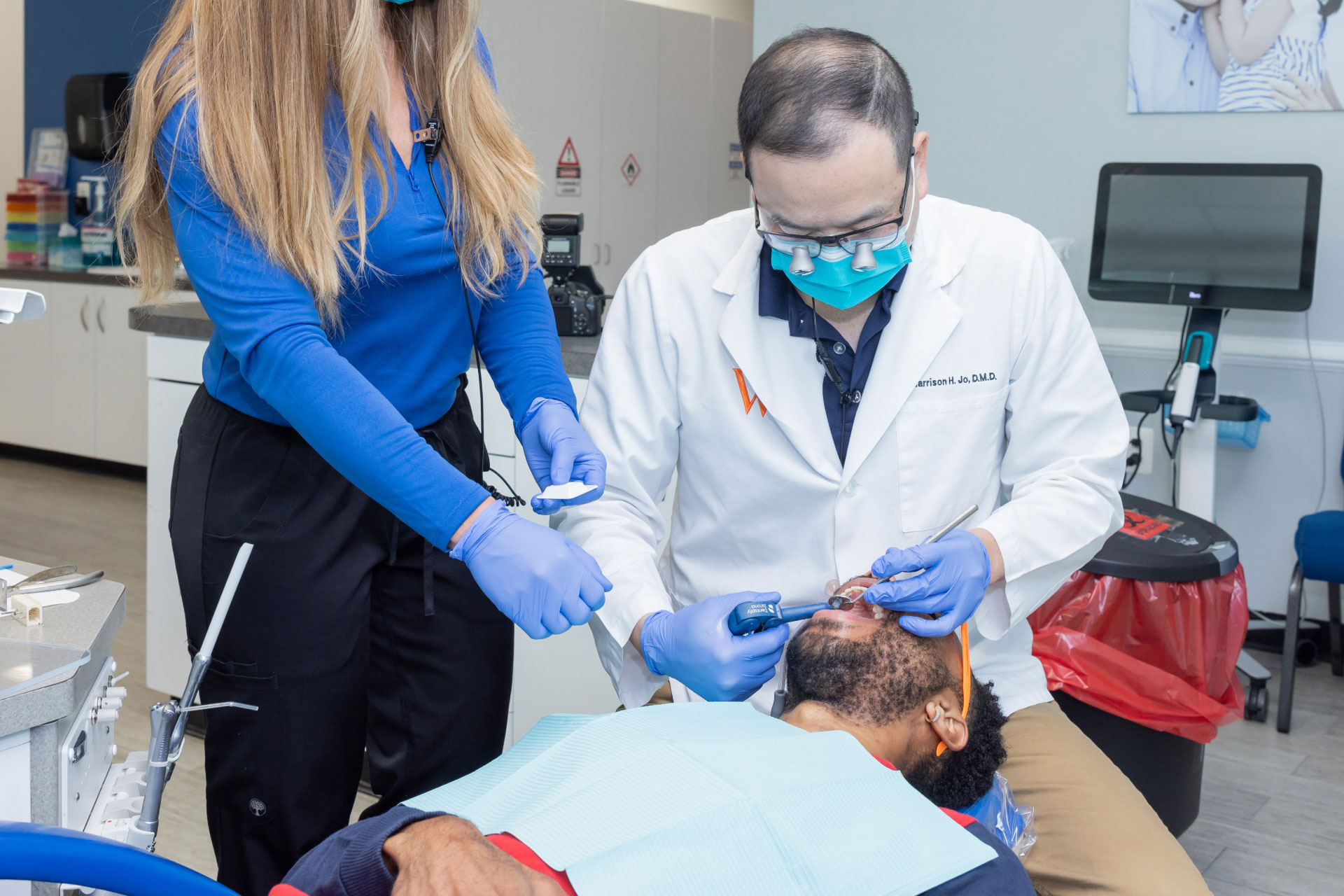Dr. Jo and assistant performing dental exam on adult patient in exam room