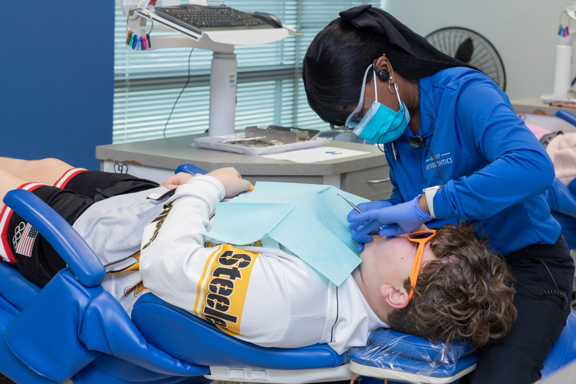 dental assistant performing dental exam on teen patient with braces in exam room