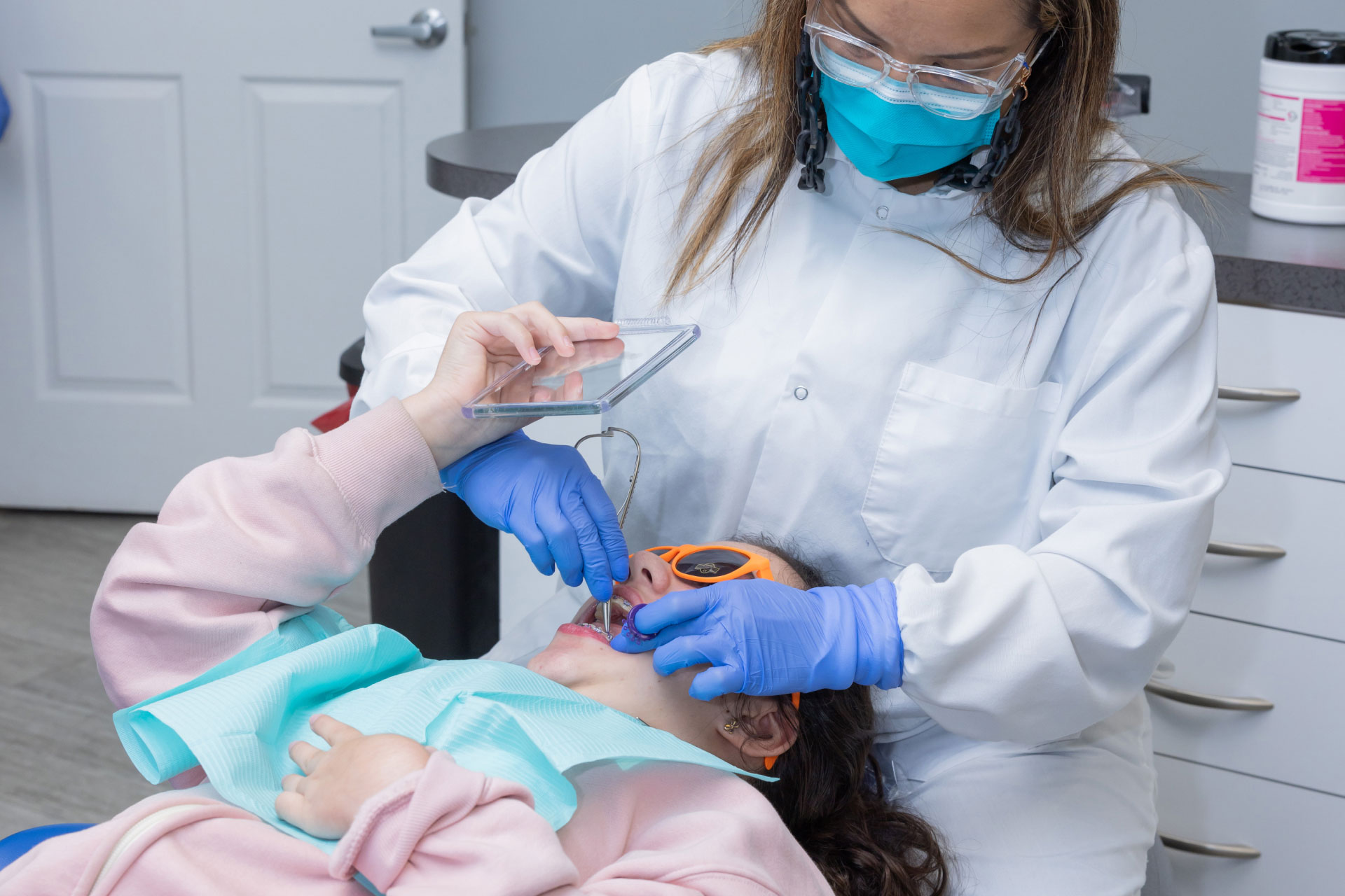 dental assistant performing dental exam on teen patient with braces in exam room