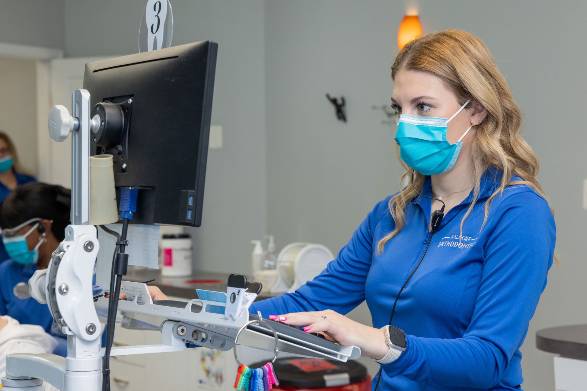 dental team member wearing mask looking at computer screen and using keyboard